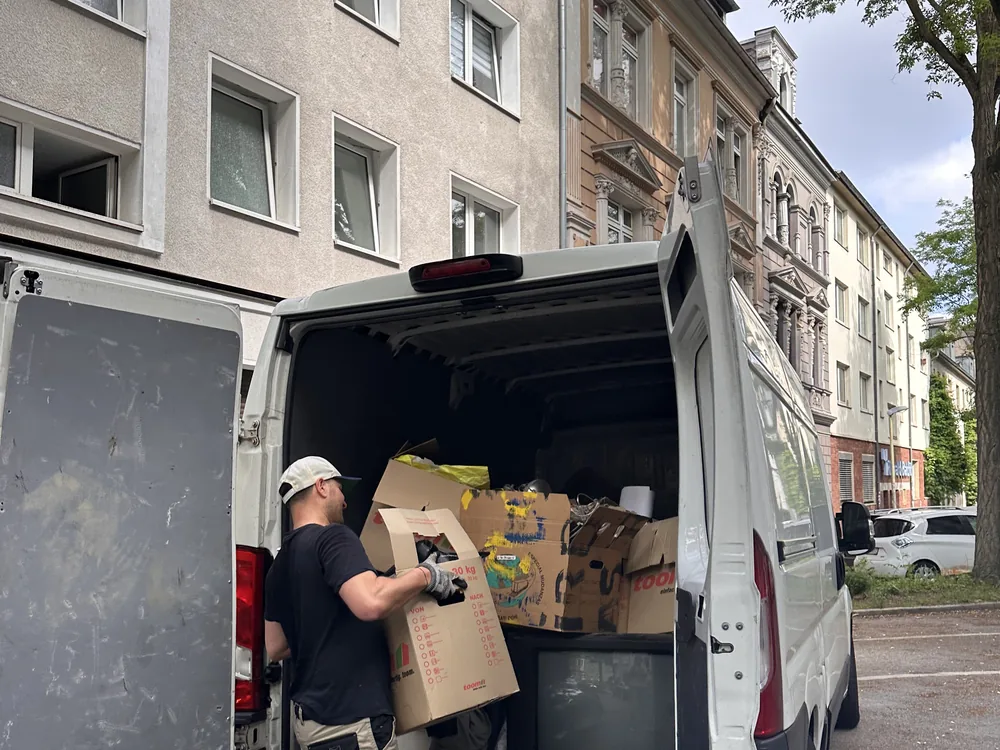 Mitarbeiter verlädt beschriftete Umzugskartons in den Transporter